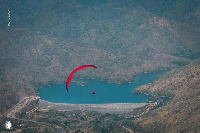 Параплан над озером и береговой дамбой — широкий план пейзажа, показывает место приземления и видовую часть маршрута.