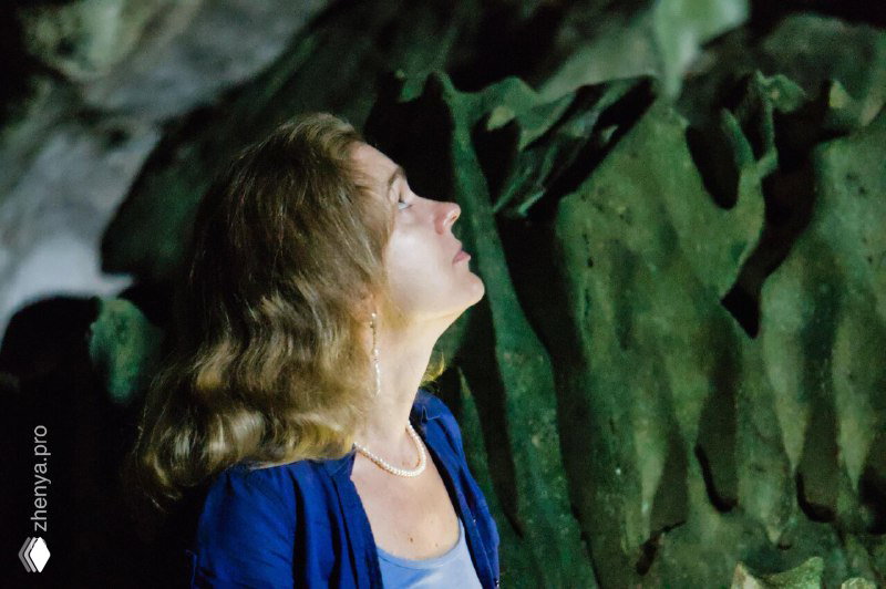 Портрет женщины в пещере или у скал с мягким боковым светом — кадр из документальной фотосессии во время выезда.