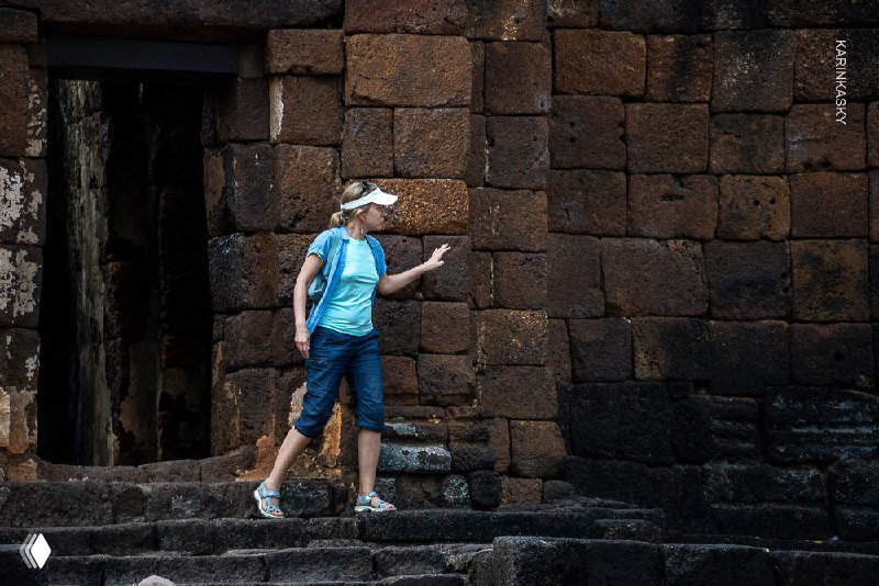 Участница в спортивной одежде у древних каменных развалин во время экскурсии — сочетание спорта и культурной программы.
