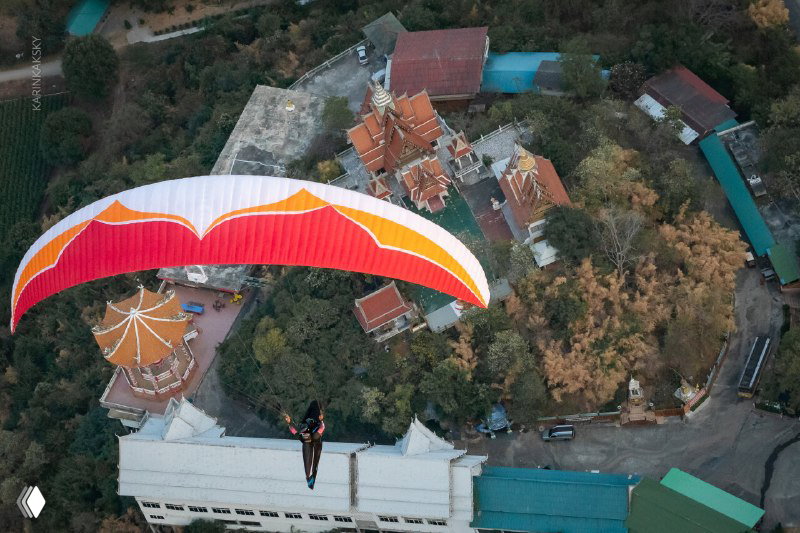 Параплан в полёте над храмовым комплексом и зданиями — пример съёмки маршрутов в южных регионах (Индия/Таиланд) с заметным рельефом и местными ориентирами.