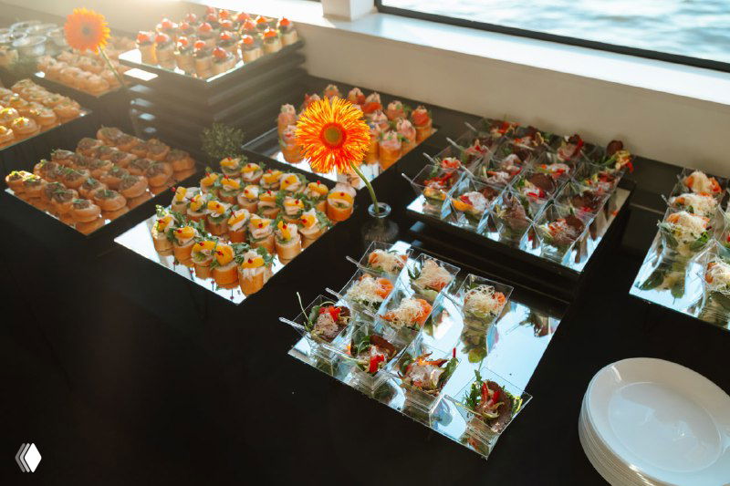 Кейтеринг на яхте: фуршетные закуски и порционные блюда на столе во время презентации, кадр подчёркивает уровень мероприятия.