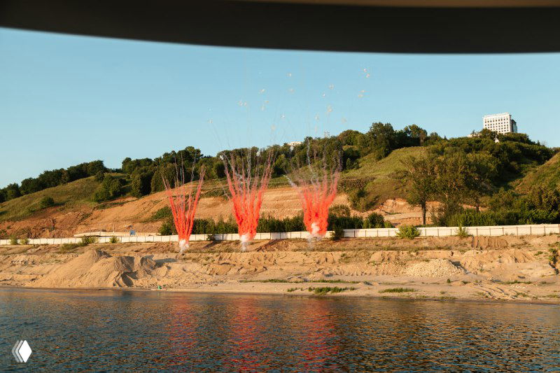 Панорамный вид на прибрежный ландшафт с художественными инсталляциями на склоне, снято с воды во время презентации проекта.