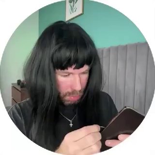 Скриншот короткого ролика: человек в тёмном парике пытается достать SIM из телефона, кадр в круглом формате, крупный план, бытовой интерьер позади.