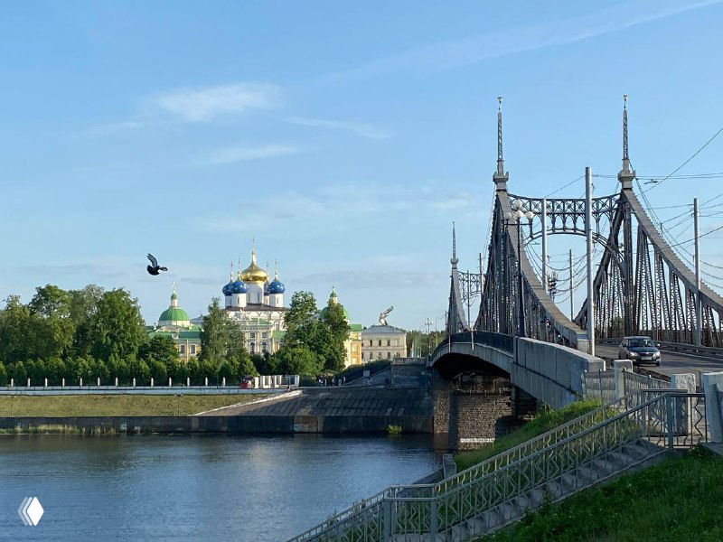 Мост через реку и купола храма под чистым небом; спокойная городская сцена, подходящая для мысленного возвращения в знакомое Место.