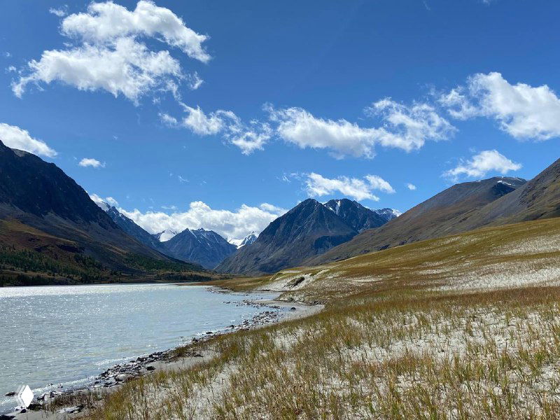 Высокогорное озеро среди горных хребтов и травянистых полей — тихое восстановительное место силы, близкое к ощущению дома.