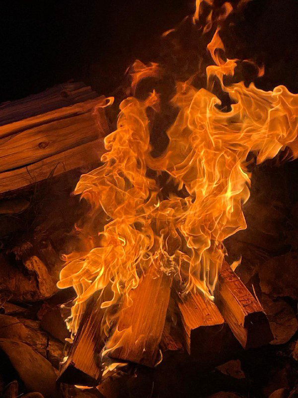 Языки пламени костра на фоне тёмного неба — образ огня как ритуала очищения, отпускания и благодарности в практиках с Местом.