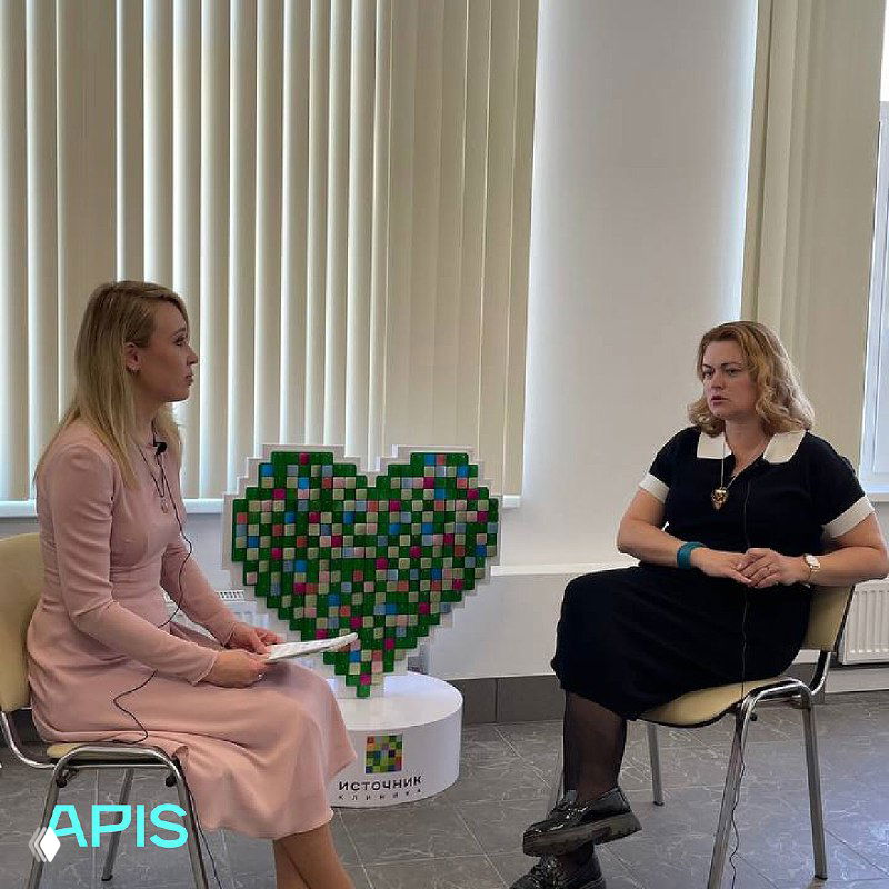 Две женщины в разговоре в кабинете на фоне декоративной инсталляции в форме сердца — сцена интервью или обсуждения, демонстрирующая глубину персонального взаимодействия и инсайты проекта.