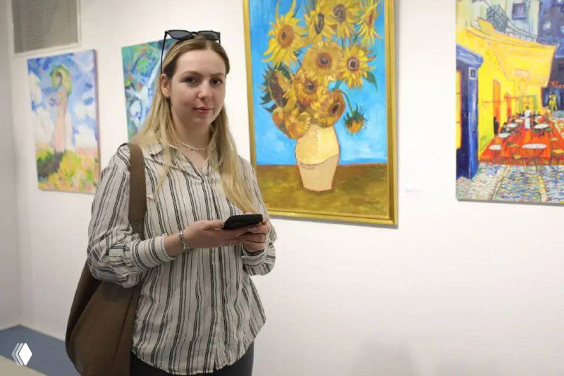 Посетительница с телефоном на фоне картины с подсолнухами в экспозиции «Лекарство для души» в музее книги Чехова на 2‑м этаже ТРК «Сити Молл».