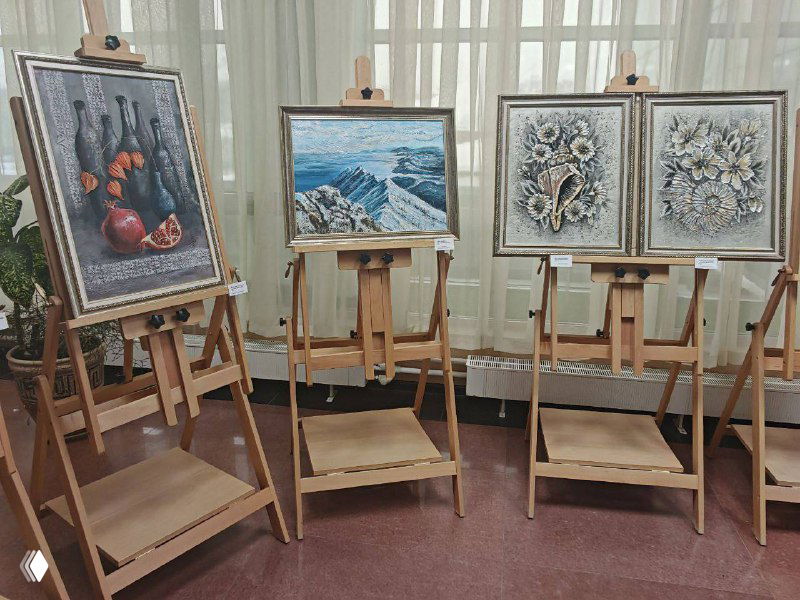 Несколько картин на мольбертах: пейзаж, цветочные и декоративные композиции, выставочные этикетки у каждой работы.