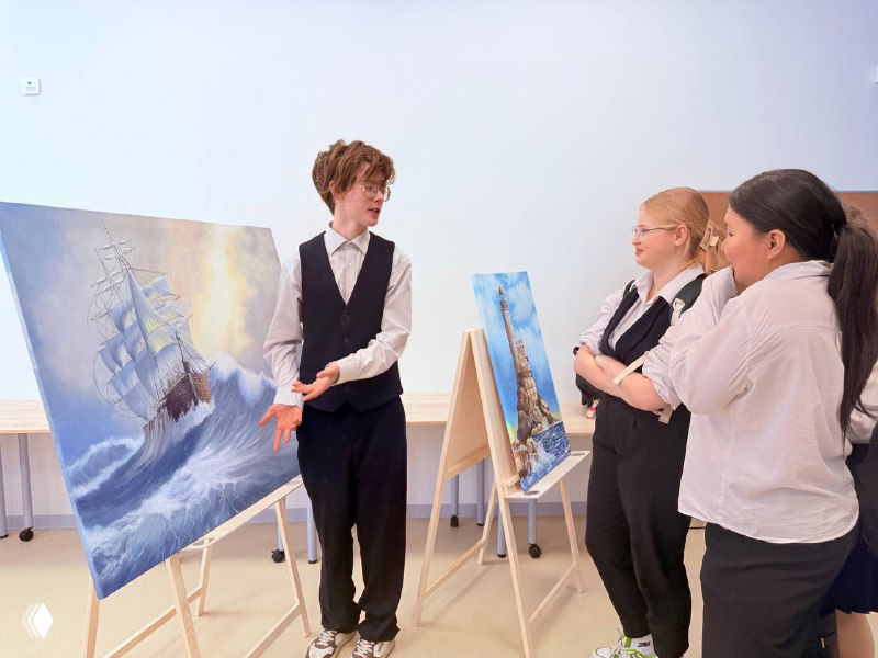 Артём презентует свои работы перед одноклассниками в школьной аудитории; мольберты с морскими пейзажами и внимательные зрители вокруг.