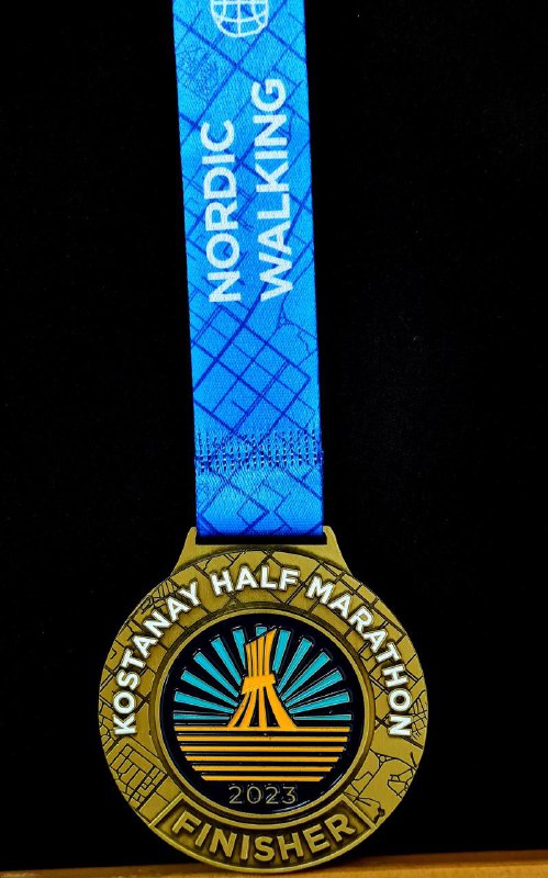 Медаль Kostanay Half Marathon 2023 на синей ленте с надписью NORDIC WALKING; крупный план медали и её декоративного центра с лучевым узором.