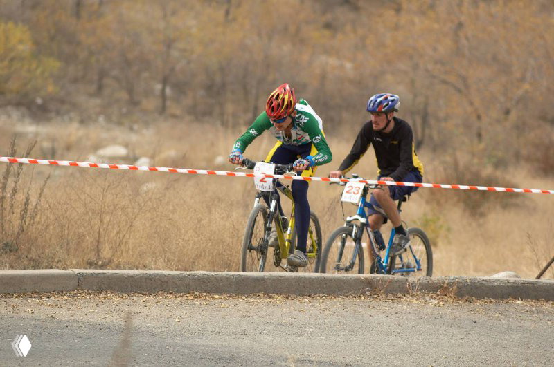 Два лидера на грунтовом участке возле ленты финиша: напряжение соревнования, пыльные следы и сосредоточенные лица участников.