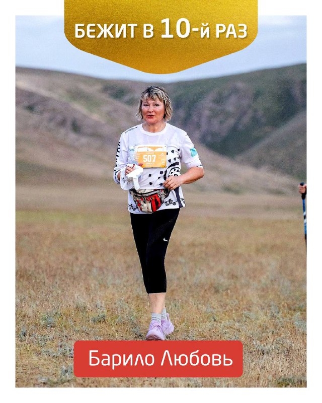 Портретная фотография бегуньи Барило Любовь с номером и баннером «Бежит в 10-й раз» на фоне степной трассы Tengri Ultra.