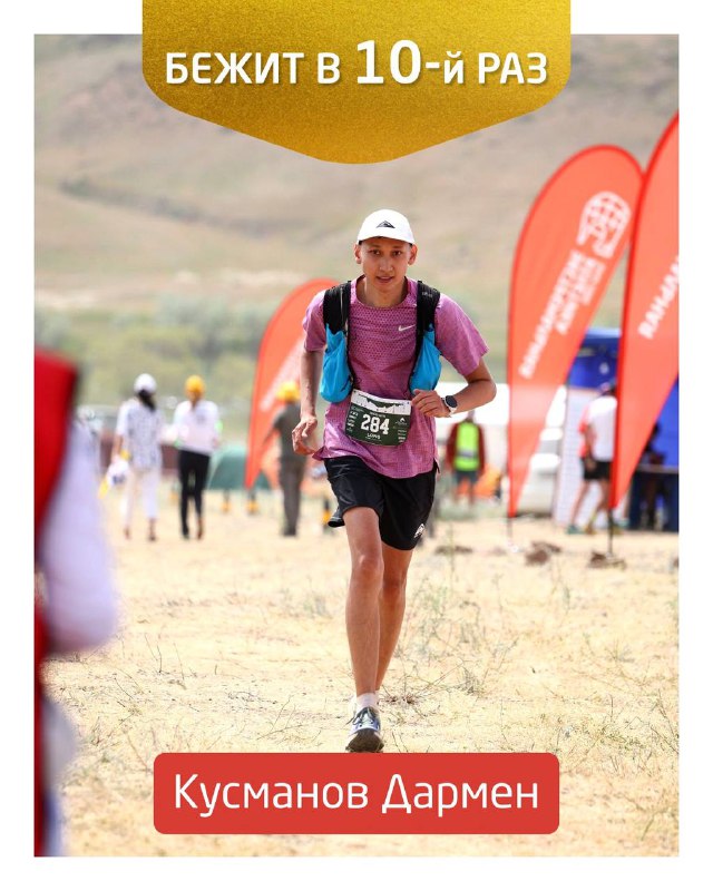 Кусманов Дармен в беге по степной трассе Tengri Ultra, кадр показывает технику и рельеф маршрута на фоне флагов мероприятия.