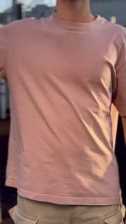 Кадр с человеком в розовой футболке: торс и верхняя часть тела на фоне уличной сцены, иллюстрация атмосферы спортивного события.