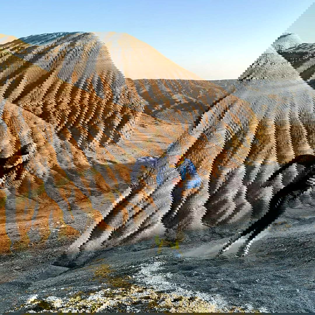 Спортсмен бежит по рябому склону бархана, подчёркивая рельеф местности Алтын-Эмель и технику трейлраннинга на неровной поверхности.