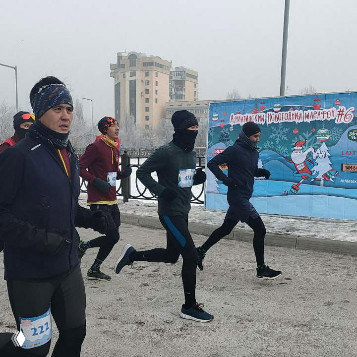 Группа бегунов стартует и бежит по заснеженному маршруту Алматинского Новогоднего марафона; кадр показывает динамику и зимние условия забега.