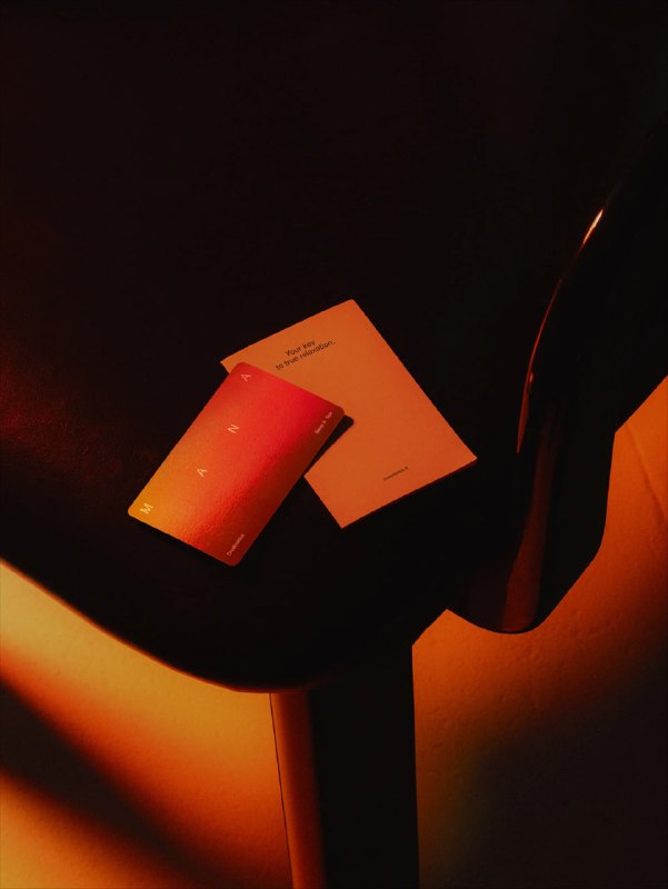 Предметный снимок на столе: блокнот и карточка в градиентных цветах бренда, подчёркивающие систему печатной айдентики Mana.