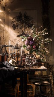 Композиция с вазой и букетом, рядом стеклянная ёмкость — фильмовая подсветка и глубокие тени создают ощущение старинной фламандской живописи в формате анимированного 3D-натюрморта.