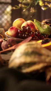 Крупный план фруктовой композиции: персики, виноград и другие фрукты на переднем плане, смягчённый фокус подчёркивает текстуру кожуры и сочность плодов в анимированном натюрморте, напоминающем фламандскую традицию.