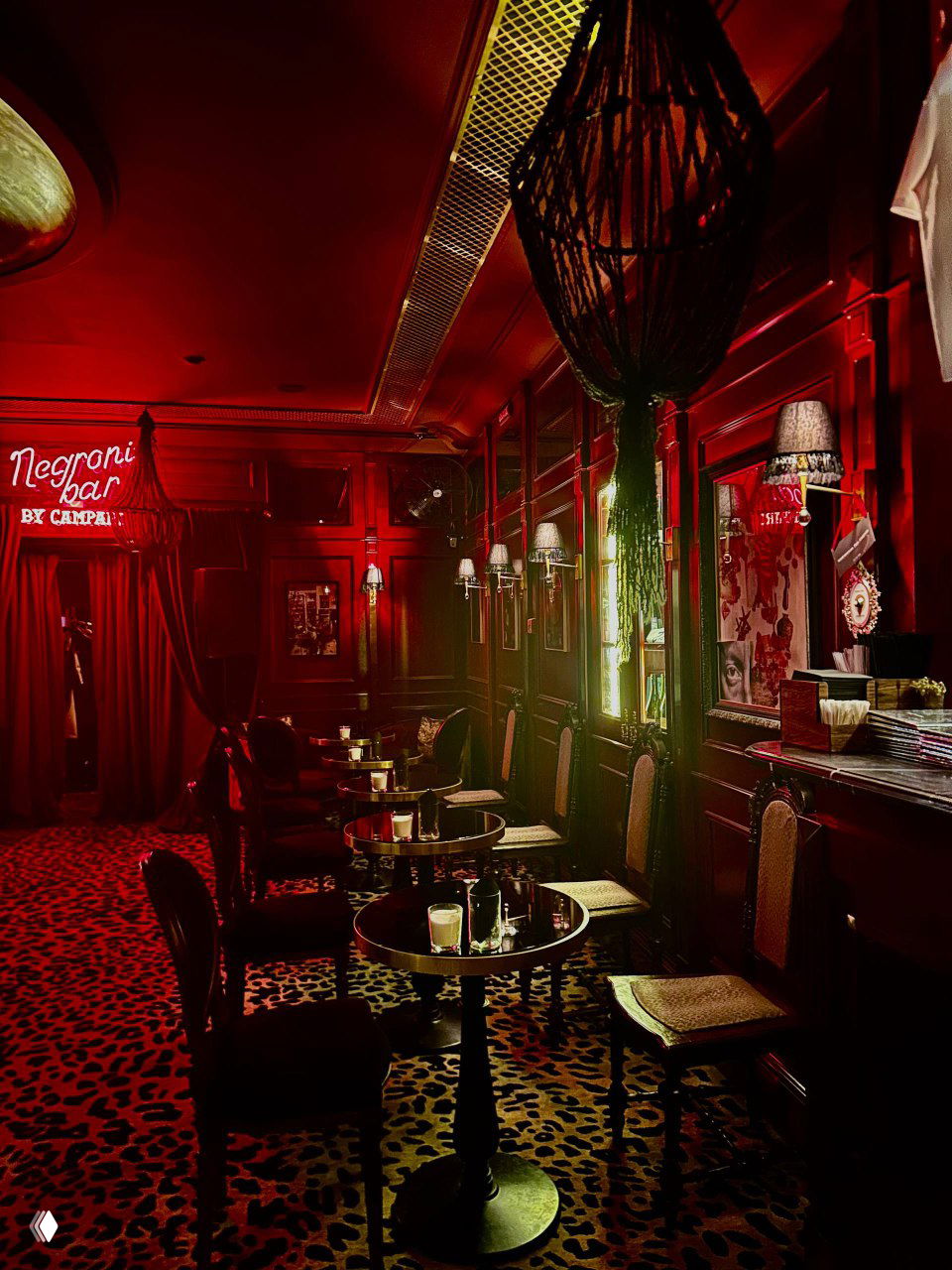 Интерьер бара с низкими столиками, креслами и леопардовым ковром в насыщенно‑красной палитре — интимное настроение и театральный декор Chez Serge.
