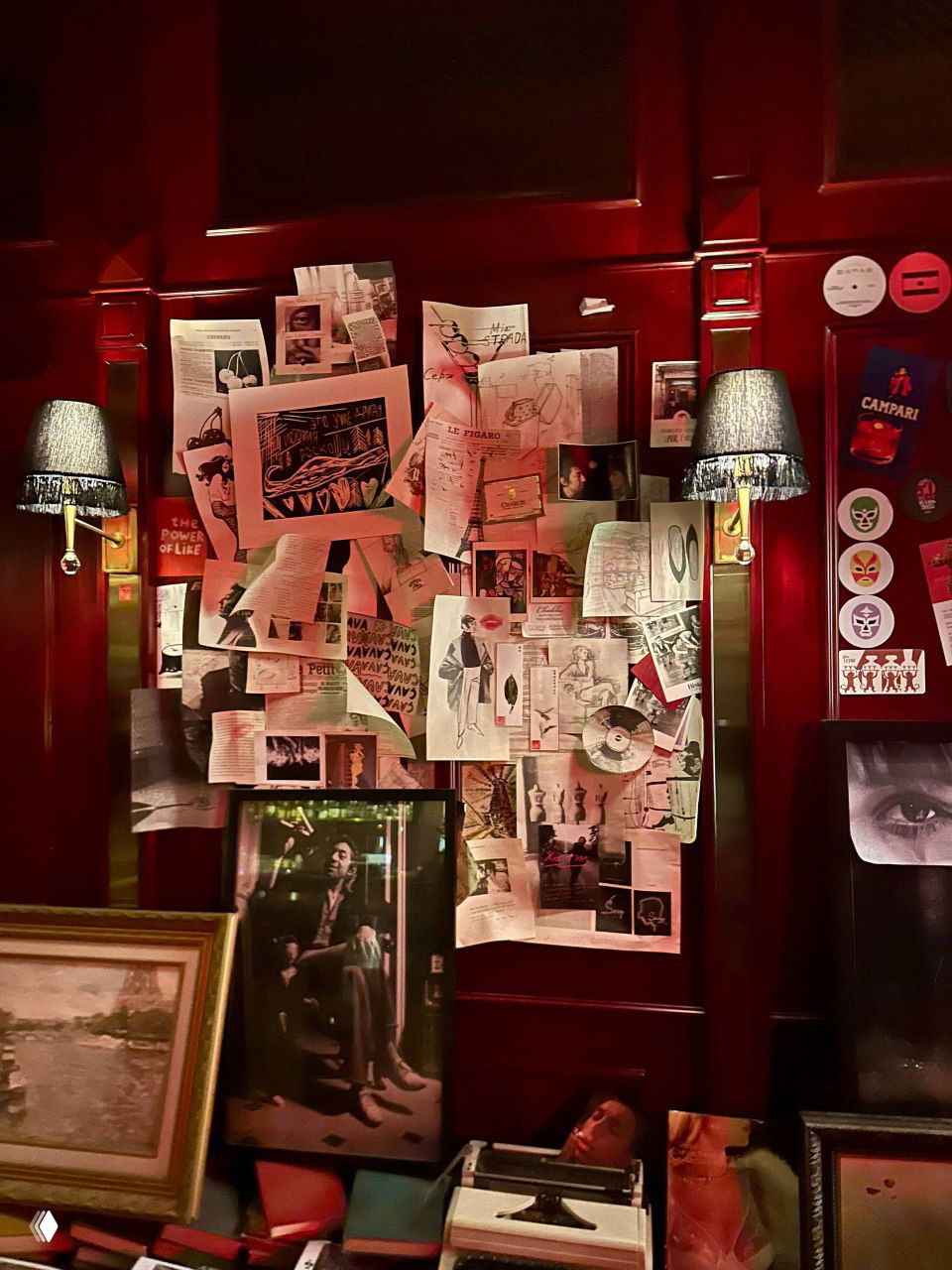 Стена, уставленная разными газетными вырезками, фотографиями и постерами в красном обрамлении — коллаж, создающий атмосферу бара и намёк на Гинсбурга.