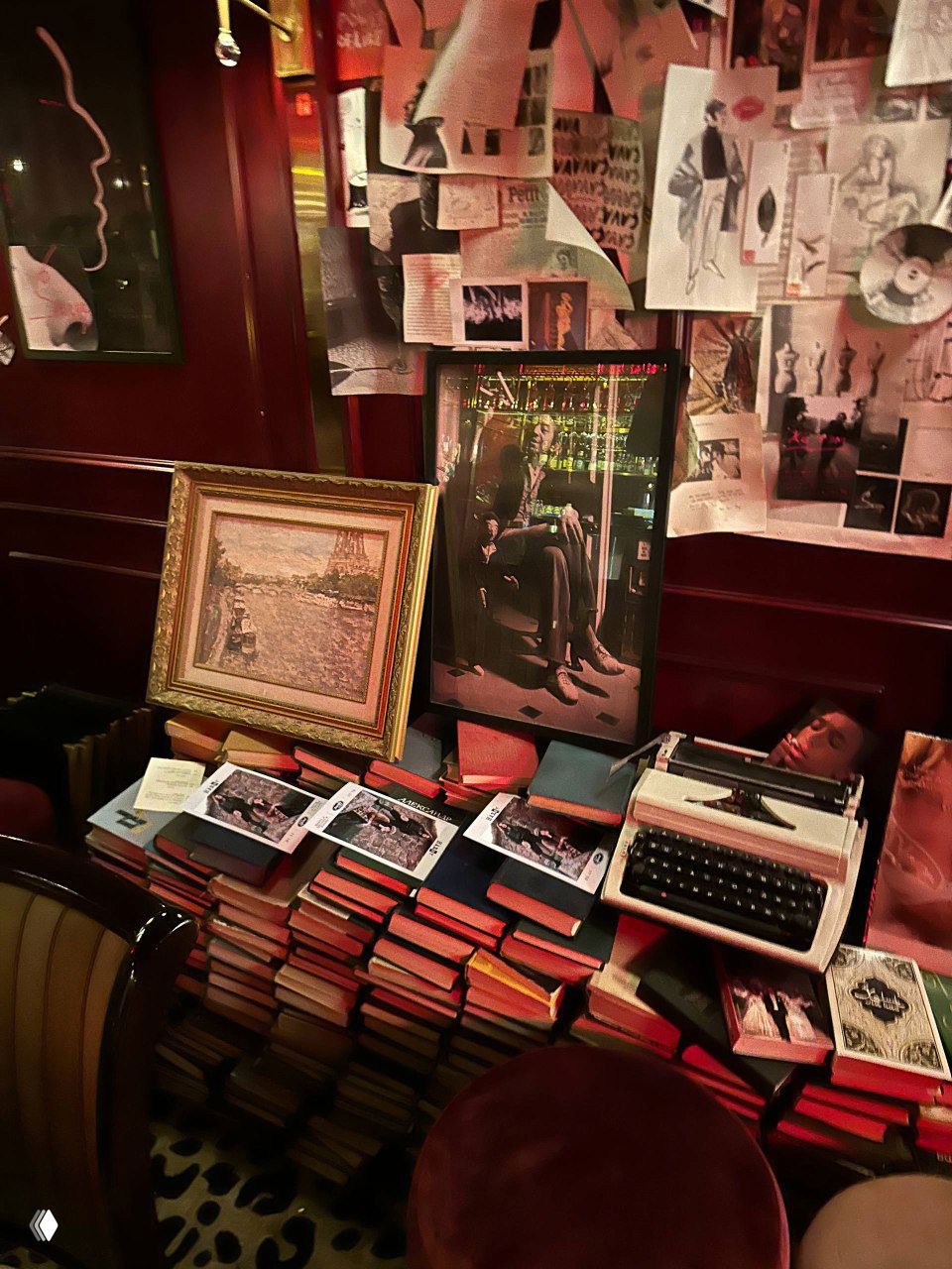 Стеллаж с книгами, рамками и печатной машинкой на фоне красной панели — элементы декора, создающие ощущение квартиры декадента в Chez Serge.