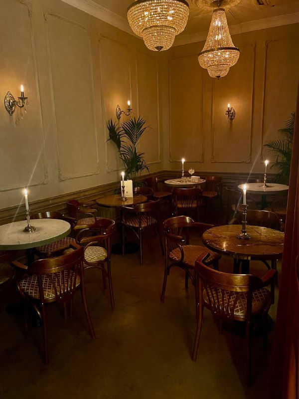 Уютный зал с люстрами, круглыми столиками и зажжёнными свечами — зона для гостей в историческом баре «Медведь».