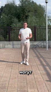 Мужчина в белой футболке стоит на улице у ограждения в кадре вертикального видео — иллюстрация ролика о банкротстве и его последствиях.