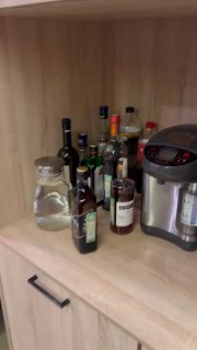 Небольшой кухонный уголок офиса: набор бутылок с напитками, кувшин с водой и электрический термопот на полке — вид зоны отдыха для сотрудников.