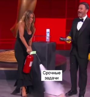 Женщина в вечернем платье применяет огнетушитель на сцене рядом с ведущим; на фото подпись «Срочные задачи».