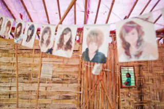 Фотографии причёсок висят в стенде парикмахерской в небольшой французской витрине; видно элементы местной уличной сцены.