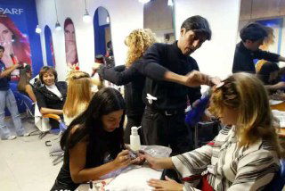 Интенсивная работа в салоне красоты: мастера одновременно делают маникюр и причёски клиентам в торговом центре Каракаса.