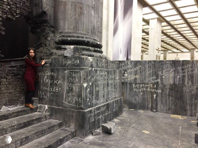 Автор стоит у бетонной мемориальной конструкции с надписями и граффити, интерьер музейной экспозиции о войне.