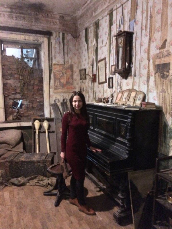 Автор в историческом интерьере с пианино и старинными предметами: домашняя сцена, музейная воссозданная комната.