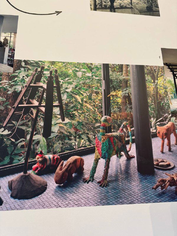 Фотография фигурок из Стеклянного дома — маленькие архитектурные фигурки и игрушечные животные на фоне растительности и интерьера дома.