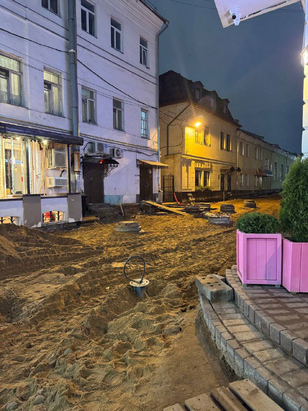 Песчаная улица вечером в Ярославле: вырытый грунт и строительные работы, фонари и витрины — нехарактерная декабрьская картина без снега.