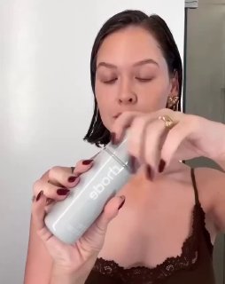 Крупный план флакона Rhode в руках автора, нейтральный фон и акцент на логотипе и форме упаковки, рекламный демонстрационный кадр.