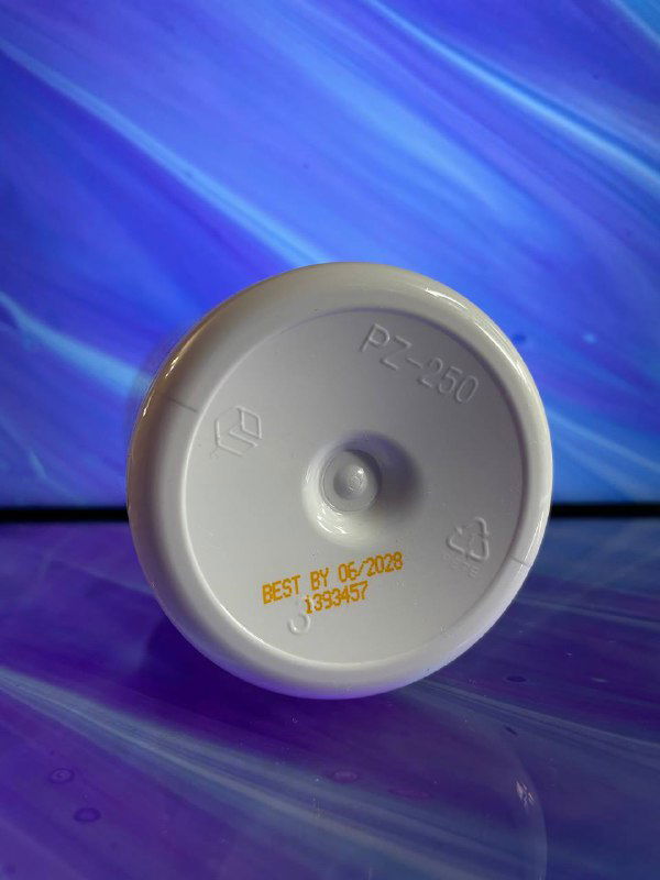 Крупный план дна пластиковой крышки бутылки NaturesPlus с маркировкой и штампом срока годности 'BEST BY 06/2028' и обозначениями переработки.