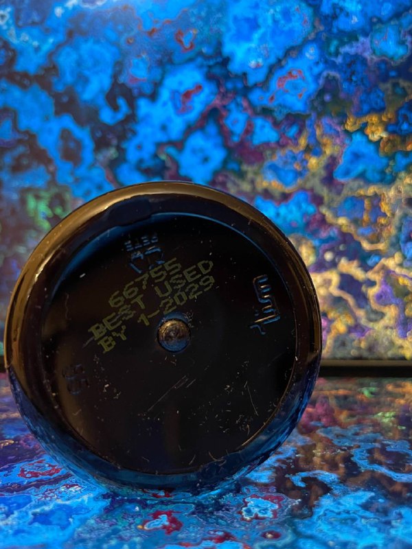 Крупное фото дна банки Carlson Mom’s DHA с отпечатанным сроком годности и серийным номером на отражающем разноцветном фоне.