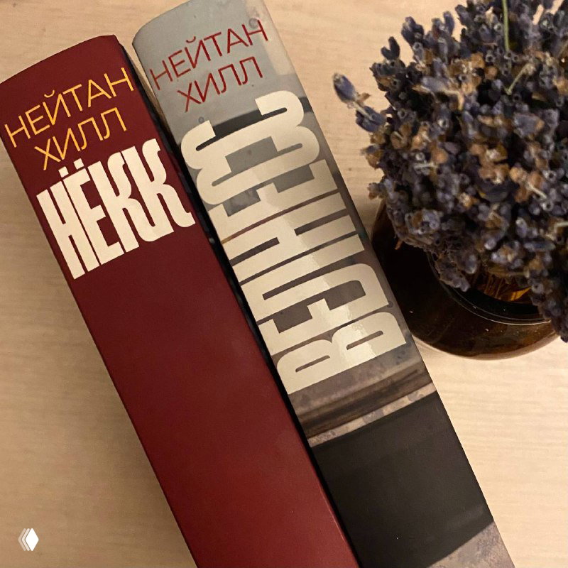 Две копии книги «Нёкк» Нейтана Хилла на столе; видно оформление корешка с крупным шрифтом названия и рядом декоративная ветка.