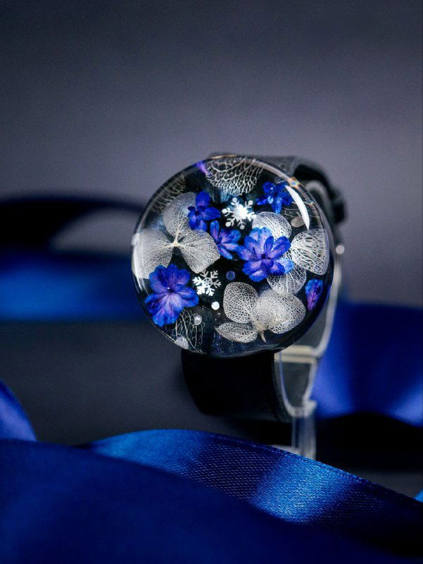 Круглая подвеска-брелок с синими и белыми высушенными гортензиями в прозрачной смоле на тёмном фоне, аккуратно снятая для показа деталей.