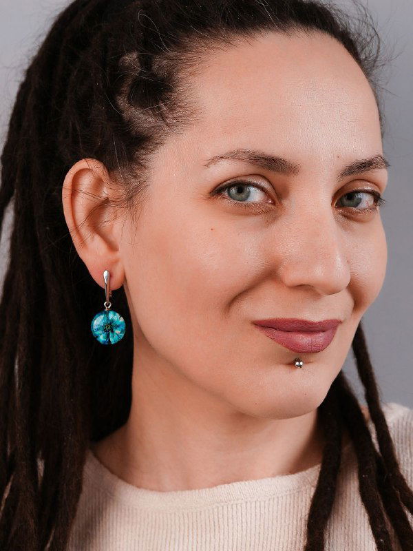 Портрет женщины в серьгах‑подвесках с бирюзовыми цветами жемчужницы в смоле, демонстрация того, как украшения смотрятся на человеке.