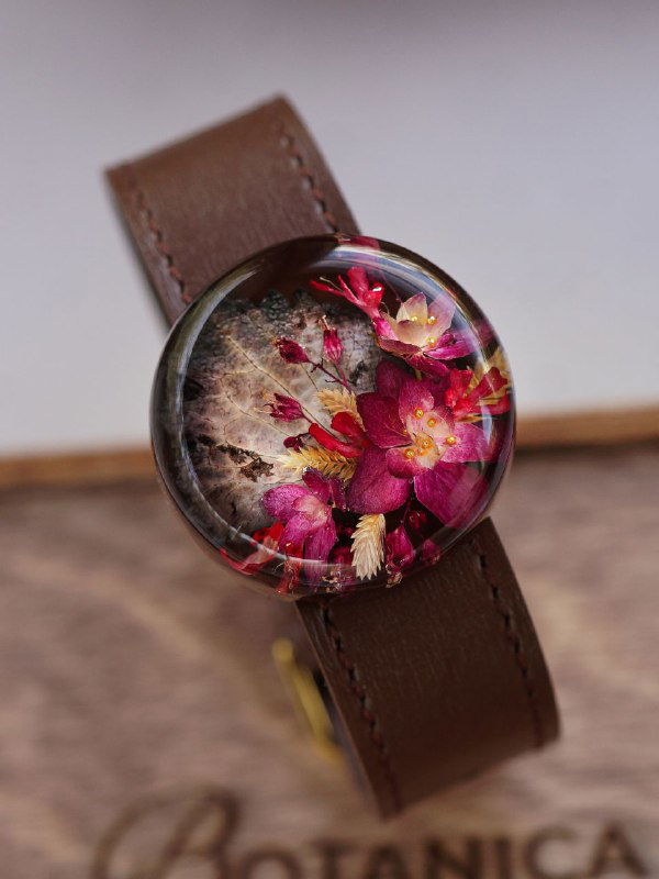 Прозрачный кабошон в браслете с насыщенными розово-бордовыми засушенными цветами и текстурным фоном — пример осенней композиции для украшений из смолы.