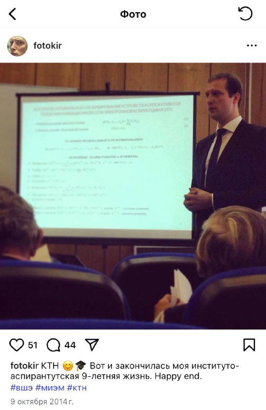 Лектор у проекционного экрана с слайдами в аудитории; кадр из офлайн-лекции или семинара, люди слушают доклад в партере.