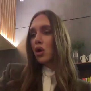 Вертикальный кадр: молодая женщина говорит в камеру в интерьере с книжными полками и чайными приборами на заднем плане — бытовой разговорный фрагмент.