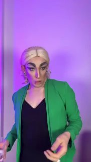 Вертикальный кадр: человек с выразительным макияжем на фоне фиолетовой подсветки, формат короткого видео или трансляции, используемый как мем-реакция.