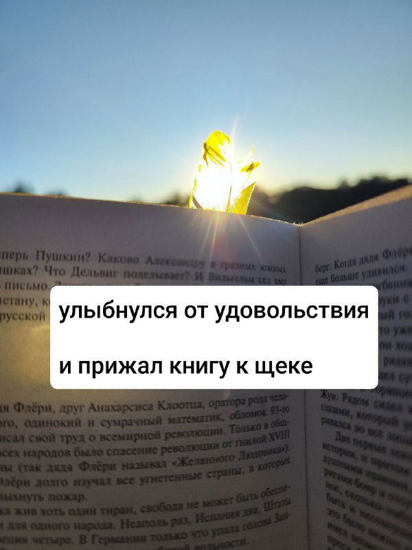 Лист бумаги или закладка у края страницы книги, светящееся солнце и размытый пейзаж на заднем плане, текст на странице частично читается.