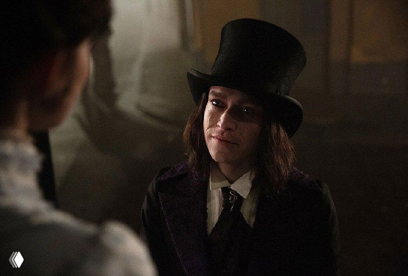 Портрет персонажа в цилиндре из «Дракула» (2025): молодой мужчина в темном прикиде с задумчивым выражением и мягким боковым светом.