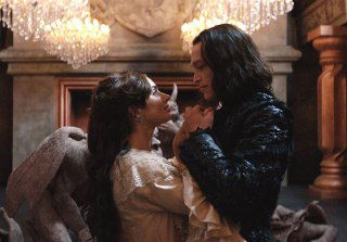 Сцена близости из «Дракула» (2025): женщина и мужчина в старинных костюмах, томные объятья у камина и барочная обстановка.